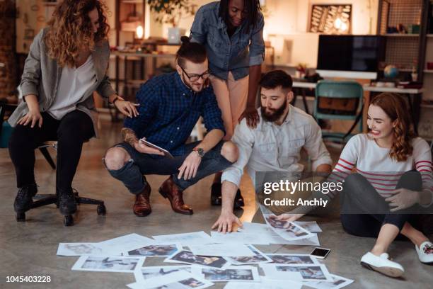 group of people sitting on the floor and looking at photos - photo editor stock pictures, royalty-free photos & images
