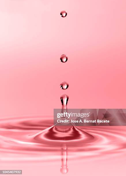 group of drops on line suspended in the air, falling down on a water surface that forms figures and abstract forms, on a pale pink background. - onde sinusoïdale photos et images de collection