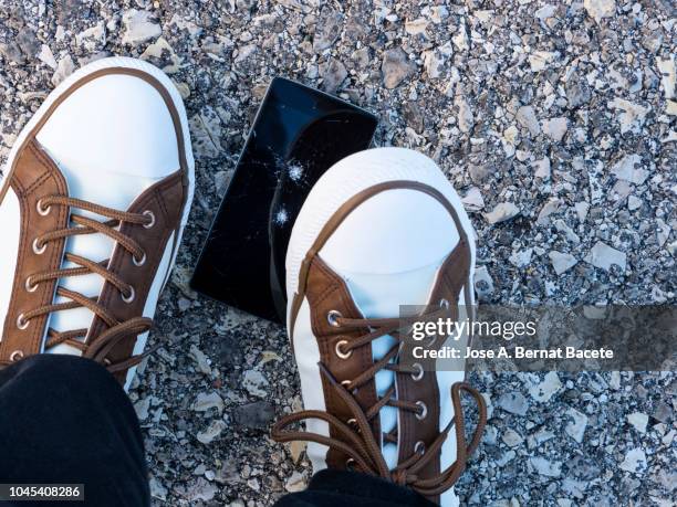 slipper of white color of a person squishing a mobile phone against the soil, outdoors. - squishing stock pictures, royalty-free photos & images