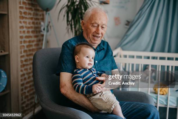 smiling baby sitting in a grandfather's lap - active baby boomer stock pictures, royalty-free photos & images