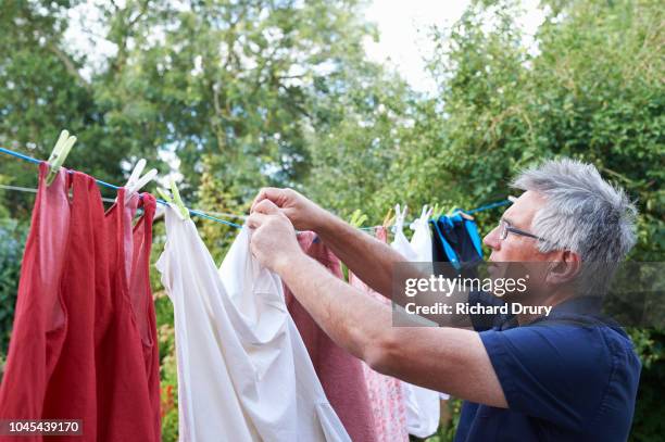 mature man hanging out the washing on the washing line - drying stockfoto's en -beelden