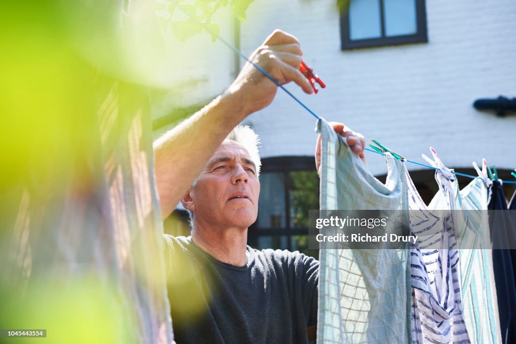 Mature man hanging out the washing on the washing line