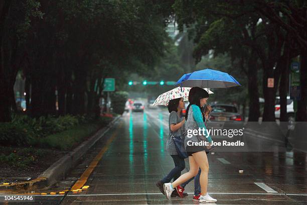 Two women walk under umbrellas in the rain from the outer bands of Tropical Storm Nicole on September 29, 2010 in Miami, Florida. The weather system...