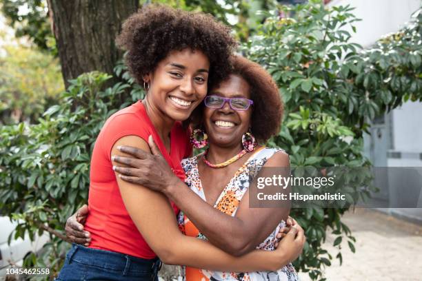 portrait of beautiful mother and daughter embracing each other while looking at camera with a toothy smile - monacle glasses stock pictures, royalty-free photos & images