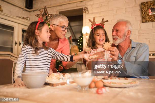 grandparents and young girls holding christmas cookies - multi generation family christmas stock pictures, royalty-free photos & images