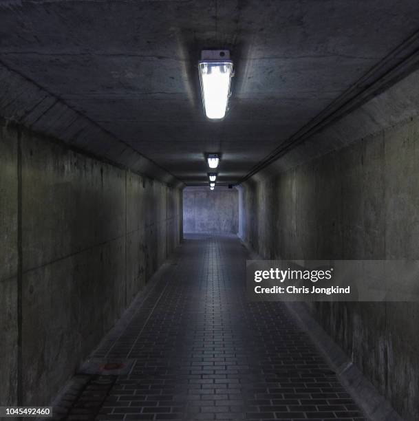 lighting over a square concrete tunnel - strassenunterführung stock-fotos und bilder