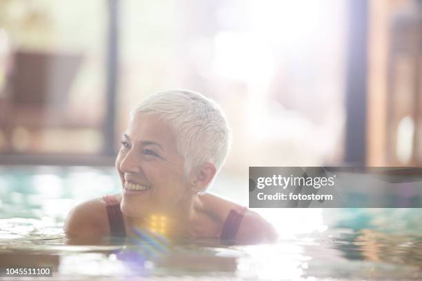 smiling mature woman in swimming pool - indoor swimming pool stock pictures, royalty-free photos & images