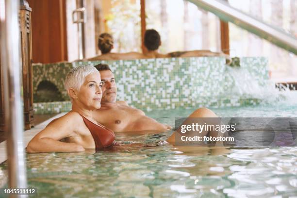 mature couple relaxing in swimming pool - shallow pools stock pictures, royalty-free photos & images