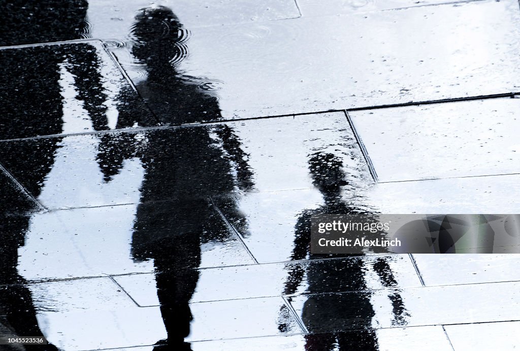 Blurry reflection silhouette of  people walking wet city street