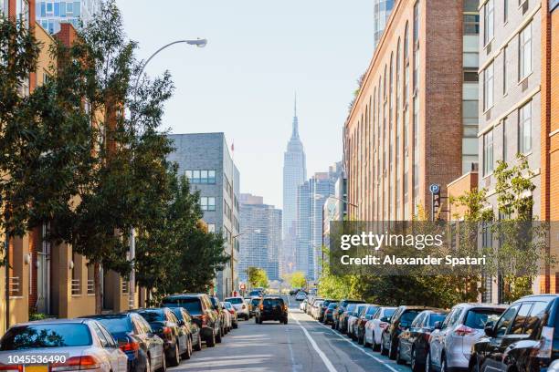 street in queens and empire state building in the center, new york city, usa - queens stockfoto's en -beelden