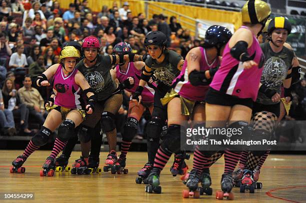 Members of the Rogue Rollergirls, dark uniform, of Fayetteville, N.C. And the Cherry Blossom Bombshells in pink of D.C., battle it out during their...