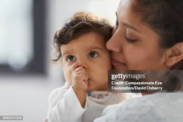 mother holding baby girl sucking thumb - thumb sucking stock pictures, royalty-free photos & images