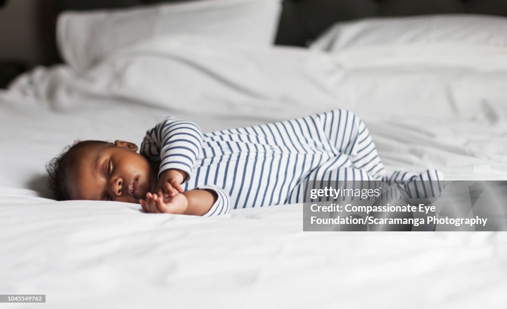 Baby boy asleep on bed