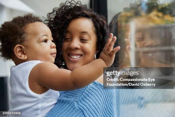 mother holding baby boy by window - women in see through tops stock pictures, royalty-free photos & images