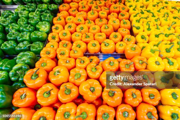 multi colored bell peppers on a market stall in the supermarket - orange bell pepper stockfoto's en -beelden