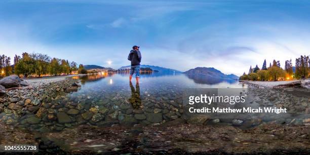 april 2017, queenstown, new zealand. a 360 view of a man as he wades out into the water of the beautiful scenic lake wakatipu at sunset. - vr 360 stock pictures, royalty-free photos & images