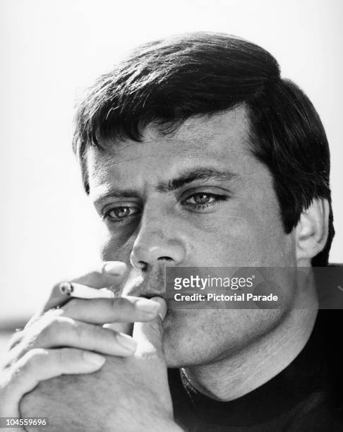 Portrait of British actor Oliver Reed holding a cigarette, circa 1960s.