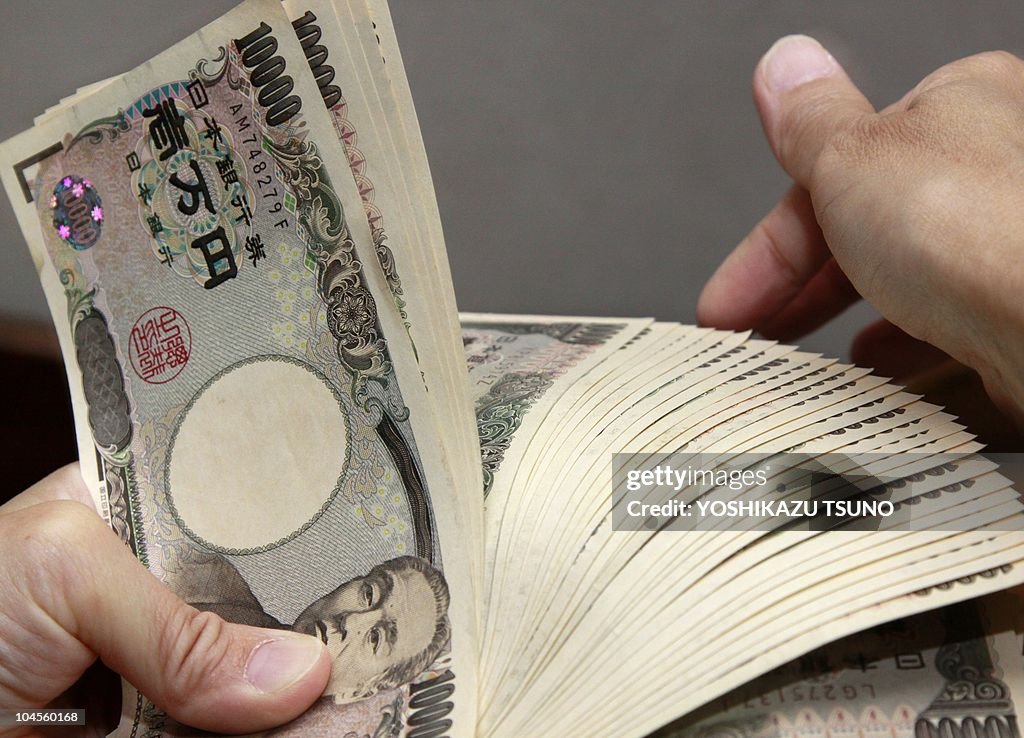 A bank teller counts 10,000 yen (118 USD