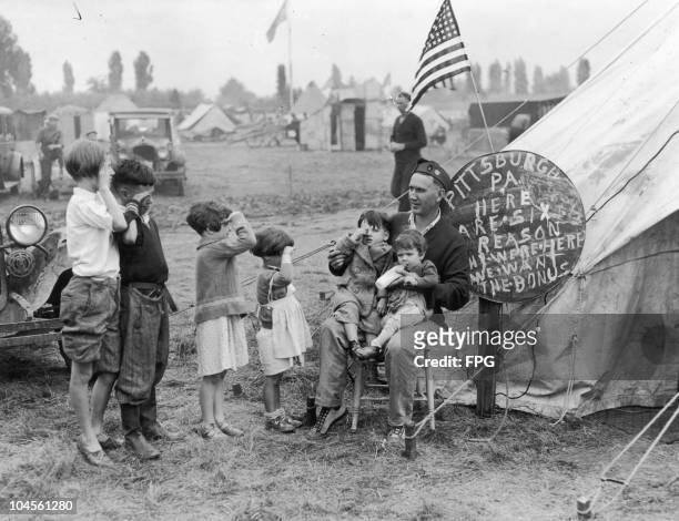 Frank Tracy and his six children saluting him in front of their tent at a encampment near Washington DC, 19th June 1932. He is part of the Bonus...
