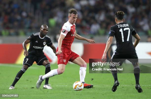 Rob Holding of Arsenal passes the ball under pressure from Innocent Emeghara and Abdellah Zoubir of Qarabag during the UEFA Europa League Group E...