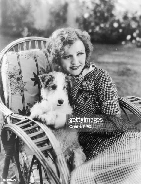 American actress Nancy Carroll and her pet dog Sockie in her garden of her home in Beverly Hills, California, USA circa 1930.