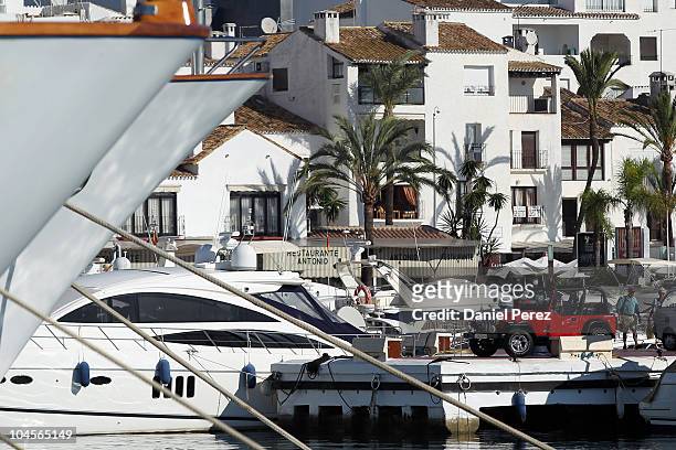 Couple stands next to a jeep parked besides luxury yachts floating in the Puerto Banus harbour on September 29, 2010 in Marbella, Spain.