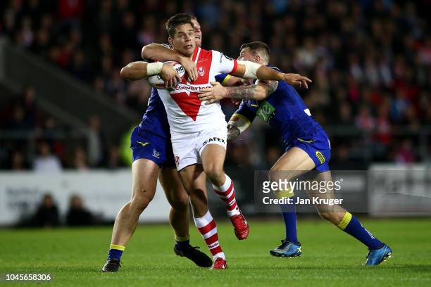 Louie McCarthy-Scarsbrook of St Helens crashes through the tackle of Jack Hughes and Daryl Clark of Warrington Wolves during the BetFred Super League...