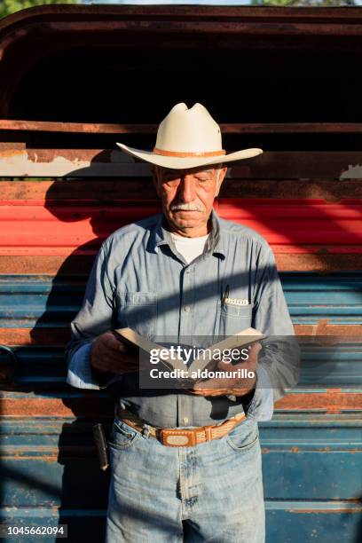 senior mexican man standing and reading the bible - bible stock pictures, royalty-free photos & images