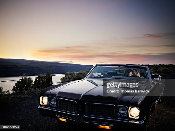young couple embracing in convertible at sunset - car passion stock pictures, royalty-free photos & images