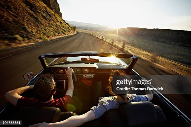 young couple driving convertible at sunset - road trip stock pictures, royalty-free photos & images