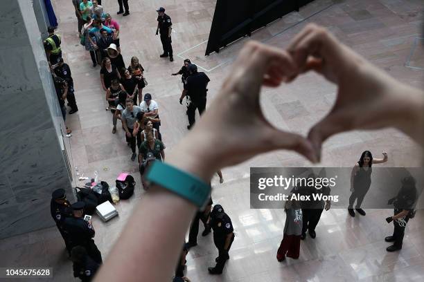 An activist forms a heart with her hands as members of U.S. Capitol Police arrest activists during a protest October 4, 2018 at the Hart Senate...