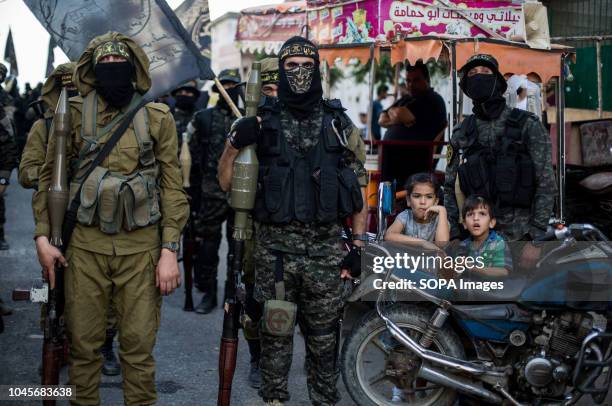 Military officers are seen standing holding weapon during the march. Members of the Palestinian Al-Quds Brigades, the military wing of the Islamic...