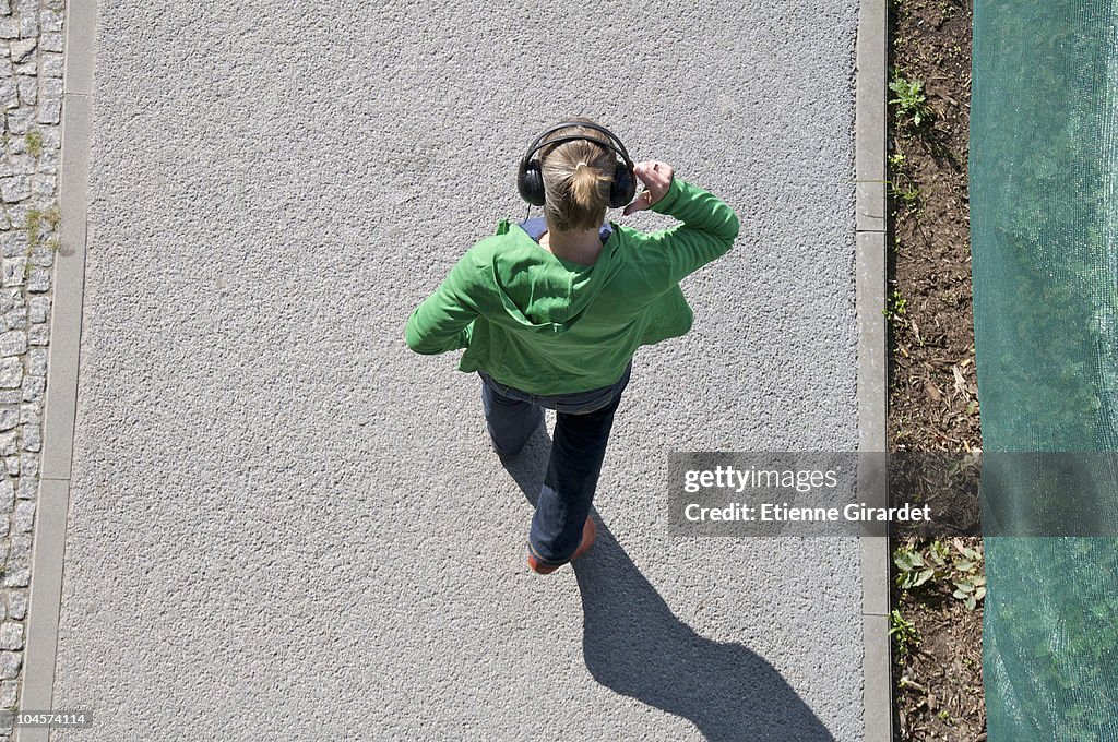 A woman wearing headphones walking on a sidewalk