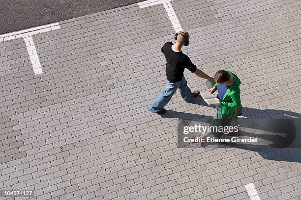 two strangers pass each other walking through a parking lot - pavement stock pictures, royalty-free photos & images