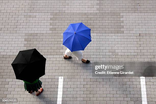 two women with umbrellas walking through a parking lot - umbrellas from above photos et images de collection