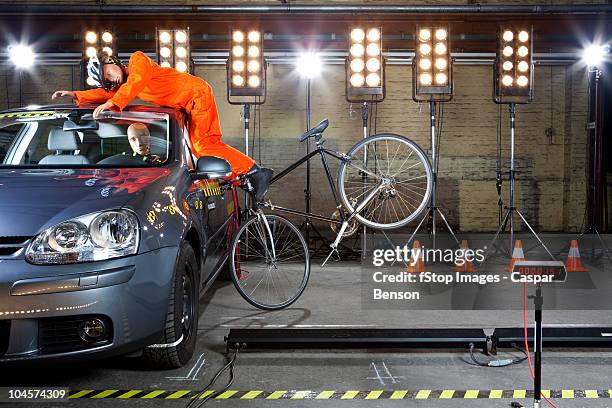 a crash test dummy on a bicycle crashing into a car - crash test dummies stock-fotos und bilder