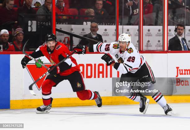 Dylan DeMelo of the Ottawa Senators charges up ice with Andreas Martinsen the Chicago Blackhawks at Canadian Tire Centre on October 4, 2018 in...