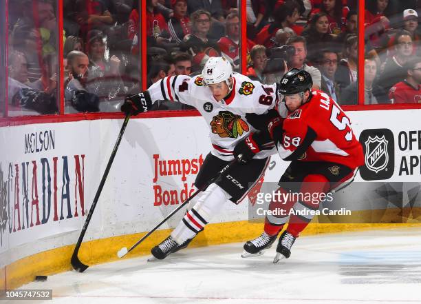 David Kampf of the Chicago Blackhawks battles for a loose puck with Maxime Lajoie of the Ottawa Senators at Canadian Tire Centre on October 4, 2018...