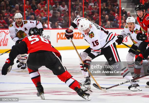 Artem Anisimov of the Chicago Blackhawks stickhandles the puck with pressure from Maxime Lajoie of the Ottawa Senators at Canadian Tire Centre on...