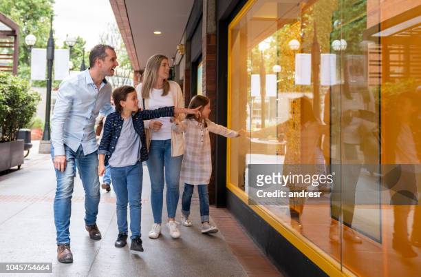 glückliche familie in der mall ein schaufenster zu betrachten - window shopping stock-fotos und bilder