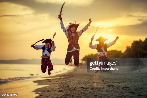 kinder spielen piraten am strand - seeräuber stock-fotos und bilder