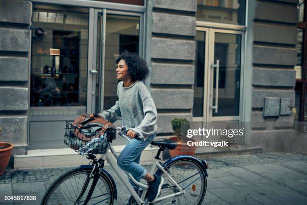 woman riding rented bicycle in a city - black woman riding bike stock pictures, royalty-free photos & images