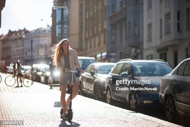 happy woman riding on an e-scooter - woman riding scooter stock pictures, royalty-free photos & images