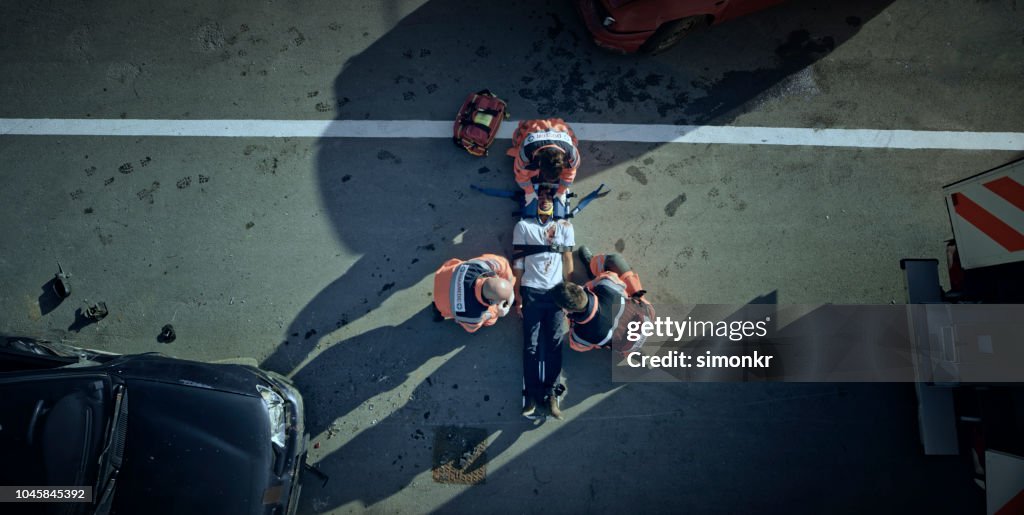 Paramedic team immobilizing male injured in car crash