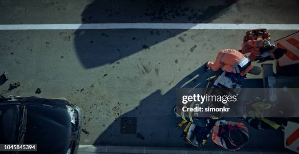 paramedics lifting injured man on stretcher and preparing him for transport - car crash top view stock pictures, royalty-free photos & images