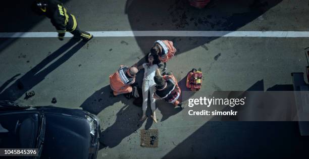 paramedic team checking vital signs of car accident victim lying on ground at car crash site - accident victim stock pictures, royalty-free photos & images