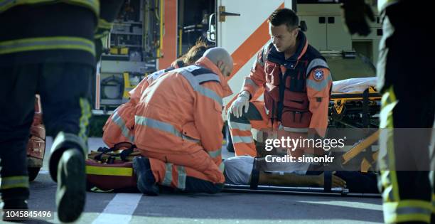 sanitäter-team fixierenden männlich bei autounfall verletzt - stretcher stock-fotos und bilder