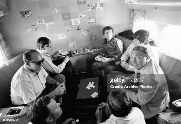 The Beatles' manager Brian Epstein, Beatles singer Paul McCartney and others play a game of cards aboard an airplane during a tour, circa 1960s.