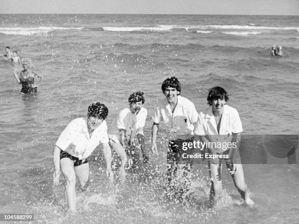 Pop group The Beatles relax on a beach in Miami, Florida. From left to right John Lennon, Paul McCartney, George Harrison and Ringo Starr, circa...