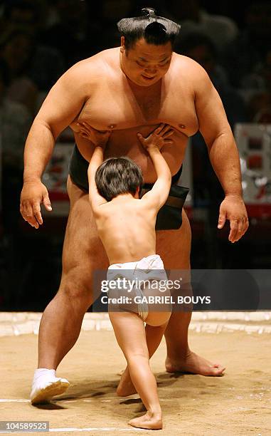 Young boy tries to push a professional sumo wrestler during an exhibition before the start of the second day of the Grand Sumo Tournament in Hawaii...